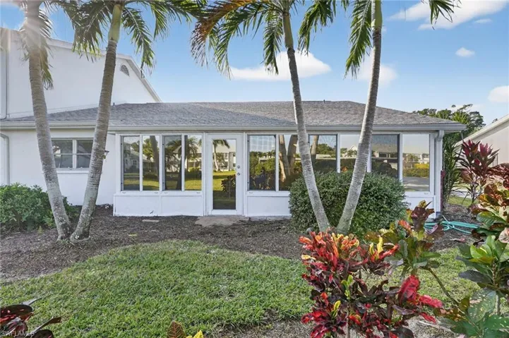 Rear view of property with roof with shingles, stucco siding, and a sunroom