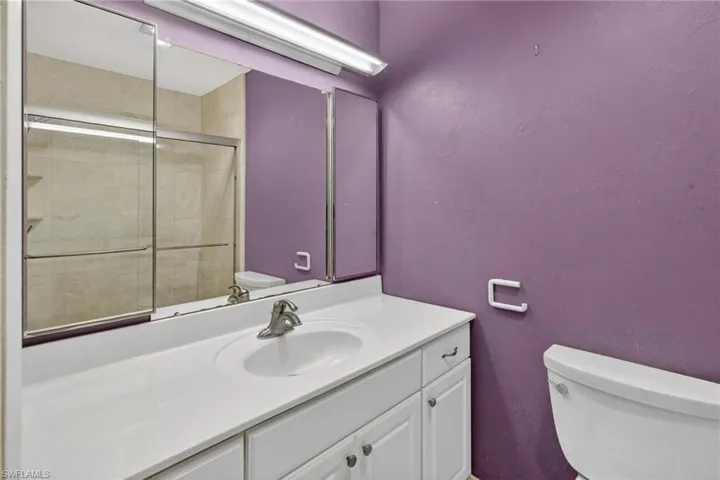 Bathroom with a shower stall, vanity, and a textured wall