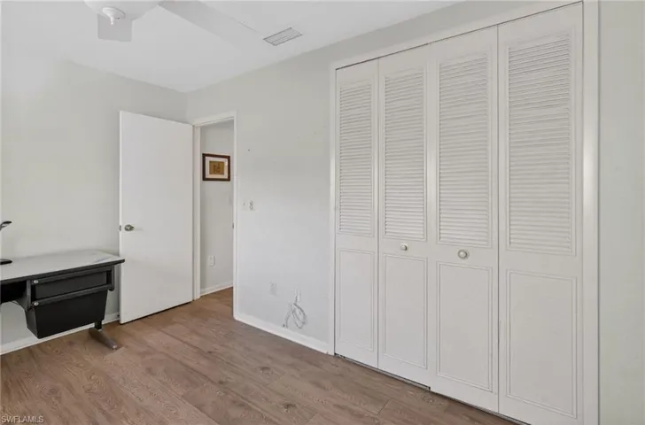 Unfurnished bedroom with wood finished floors, a closet, and a ceiling fan
