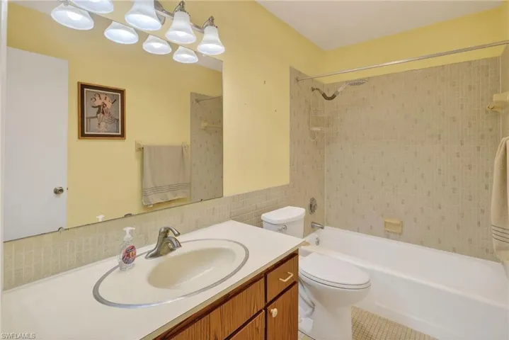 Full bathroom with tub / shower combination, vanity, and tile walls