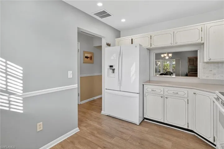 Kitchen featuring a chandelier, white appliances, light countertops, light wood-type flooring, and white cabinets