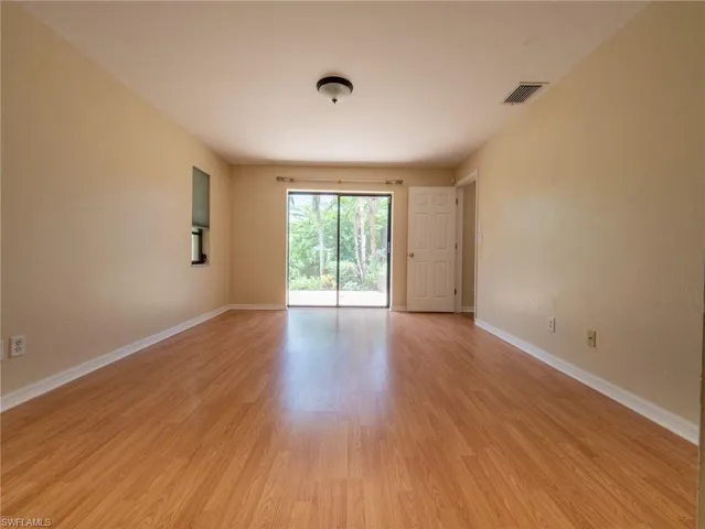 Expansive room featuring wood-finish flooring, neutral-toned walls, and a recessed window