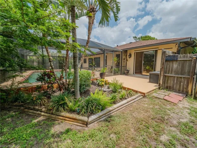 Screened-in pool area featuring a patio deck and mature landscaping