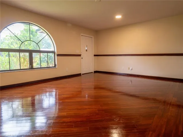 Room featuring wood flooring, a half-round transom window, recessed lighting, and a white paneled door