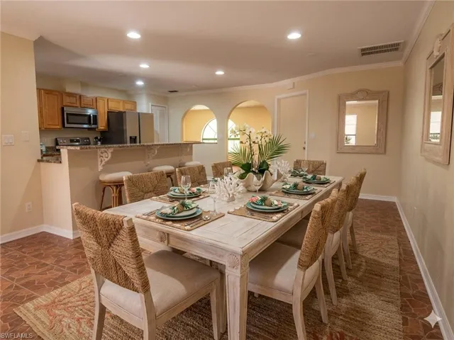Dining area featuring a wood-finish dining table and tile flooring, with an arched opening to an additional room
