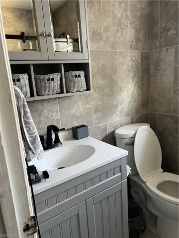 Bathroom featuring vanity, toilet, and tile walls