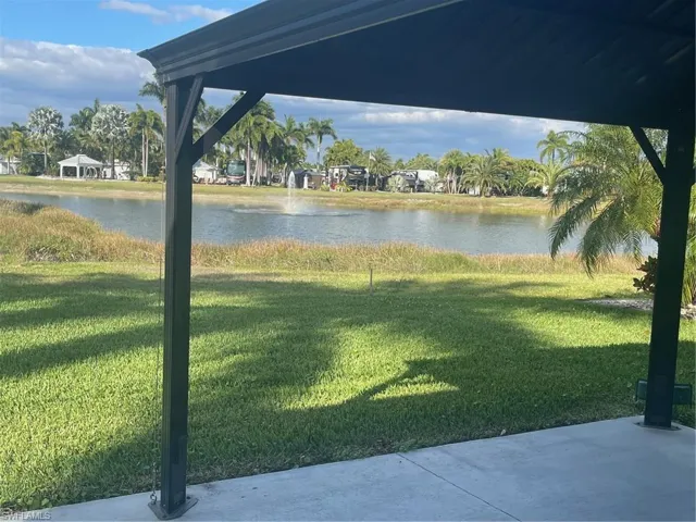 View of green lawn featuring a water view and a patio area