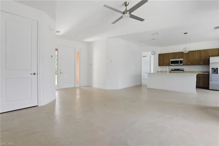 Unfurnished living room with a ceiling fan and baseboards