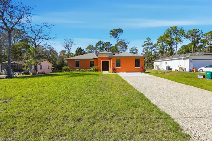 View of front of house with a front yard, stucco siding, and gravel driveway