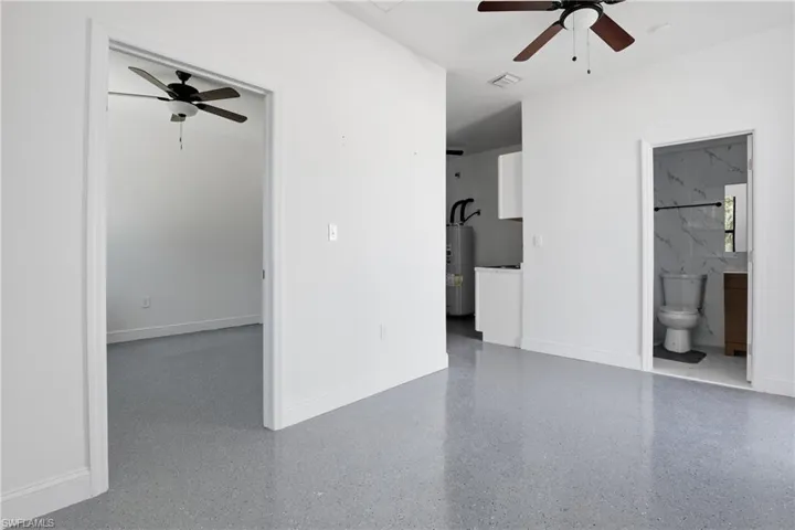 Unfurnished living room with ceiling fan and water heater