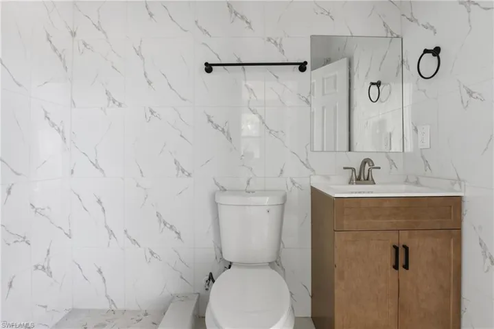 Full bath with tile walls, vanity, and a shower