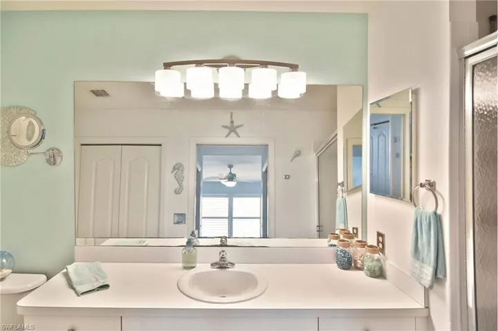 Bathroom featuring vanity, a stall shower, and a closet