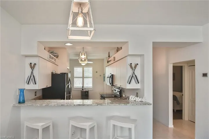 Kitchen featuring white cabinetry, a breakfast bar, stainless steel appliances, and light stone countertops