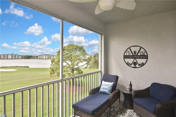 Sunroom / solarium with a balcony, a ceiling fan, view of golf course, and a water view