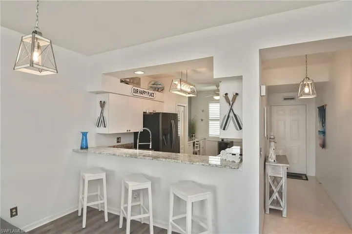 Kitchen with hanging light fixtures, a kitchen breakfast bar, stainless steel refrigerator with ice dispenser, and a peninsula