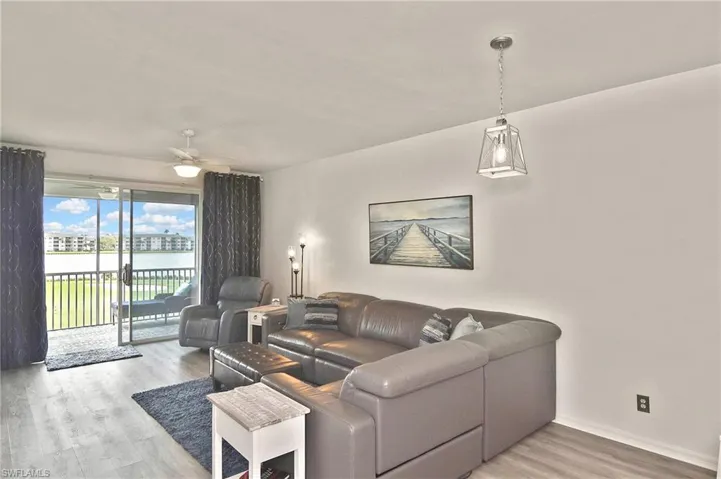 Living room featuring light wood-style flooring, ceiling fan, and a water view