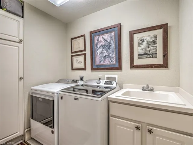 Laundry room featuring separate washer and dryer, a textured ceiling, cabinets, and sink