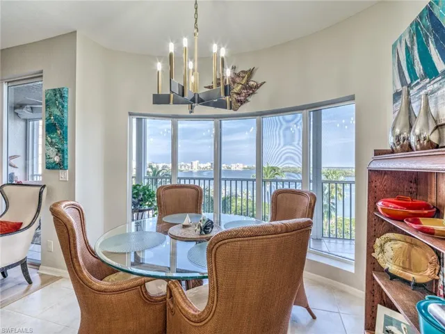 Dining room with light tile patterned floors, a healthy amount of sunlight, an inviting chandelier, and endless water views