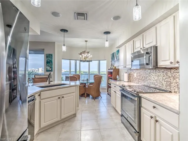 Kitchen with a notable chandelier, white cabinetry, decorative light fixtures, stainless steel appliances, and sink