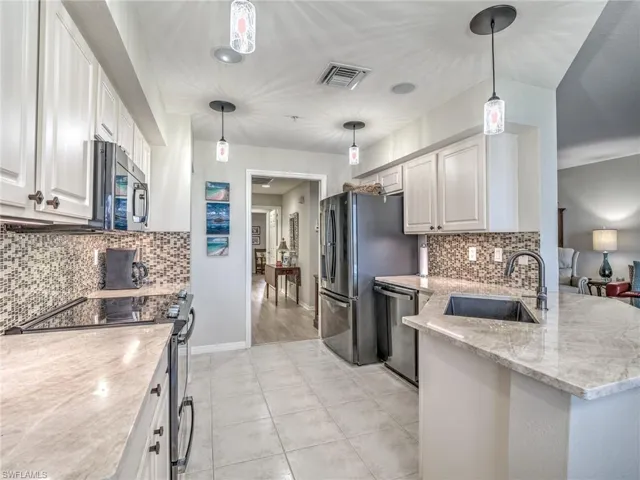 Kitchen featuring sink, decorative light fixtures, appliances with stainless steel finishes, and white cabinetry