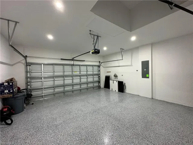 Spacious garage featuring a durable epoxy speckled floor, recessed lighting, an automatic garage door opener, and an access panel