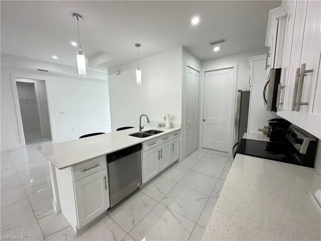 Kitchen featuring white shaker cabinetry, stainless steel appliances, and light-toned quartz countertops