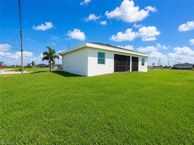 Expansive green lawn surrounds a white stucco residence with multiple windows and a screened lanai