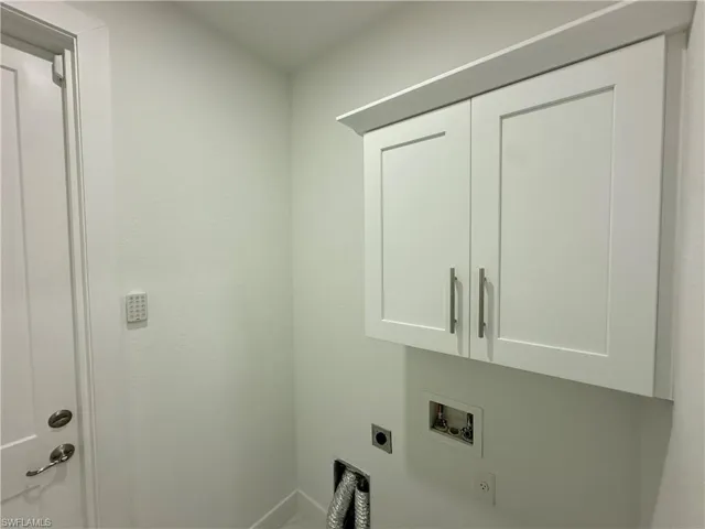 Laundry area featuring white shaker-style cabinetry with brushed nickel hardware, a utility door with matching hardware, and light-colored walls