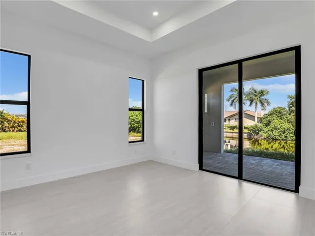 Unfurnished room with a raised ceiling, recessed lighting, and a water view