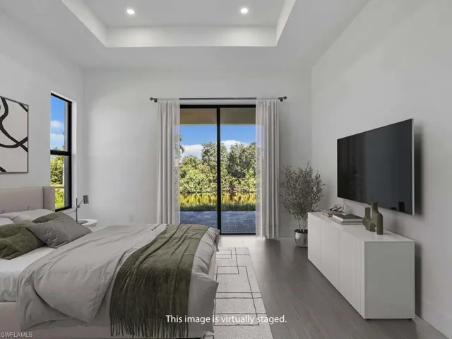 Bedroom with access to exterior, a raised ceiling, light wood-type flooring, and recessed lighting