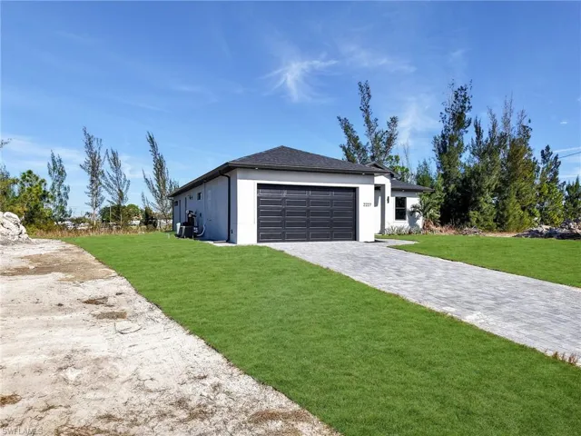 View of front of house featuring decorative driveway, a garage, a front yard, and stucco siding