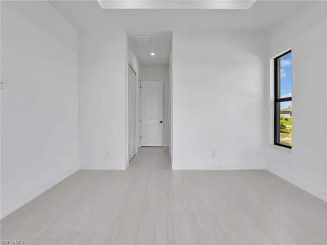 Spare room featuring light wood-style floors, a raised ceiling, and recessed lighting