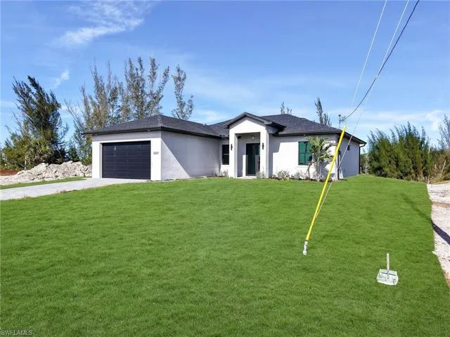 View of front of home featuring driveway, a front lawn, stucco siding, a garage, and a shingled roof
