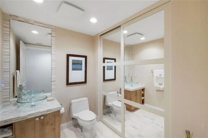 Fourth full bathroom with a hidden tub & shower beyond the sliding mirror wall.