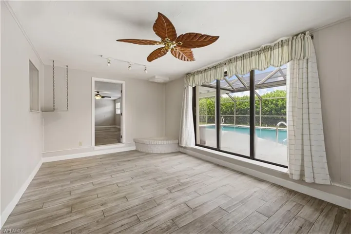 Spacious interior room featuring wood-finish flooring, a decorative ceiling fan, and track lighting