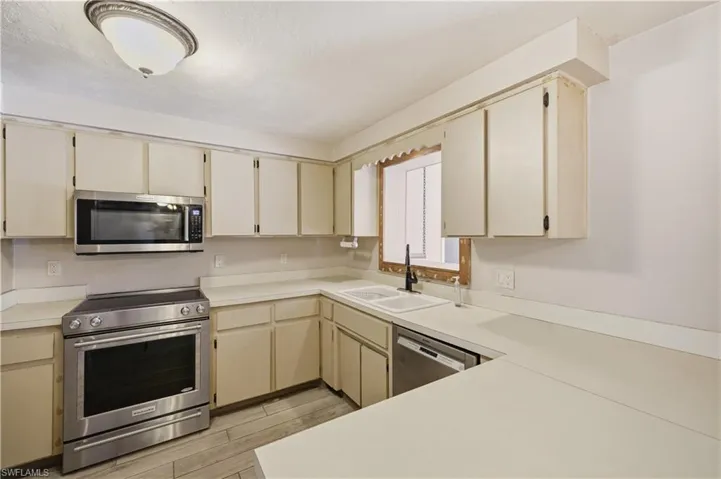 Kitchen featuring extensive off-white cabinetry, light-toned countertops, and wood-finish flooring