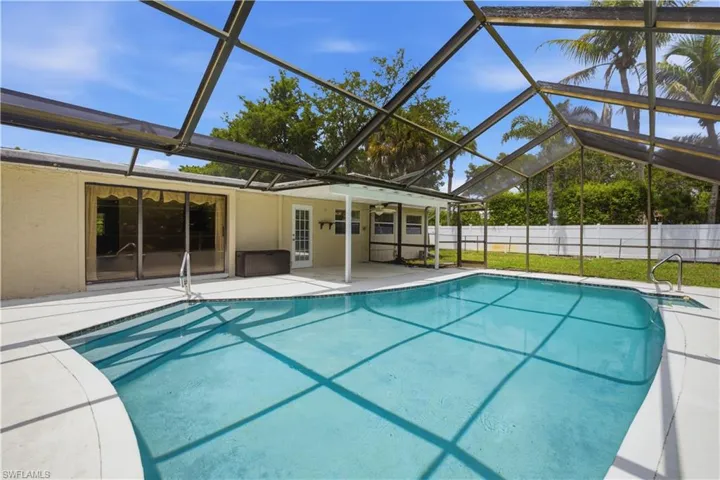 Screened-in swimming pool featuring a curved entrance and white coping