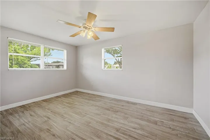 Room featuring wood-finish flooring, light grey painted walls, and white trim