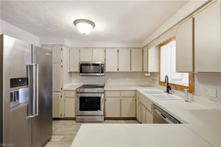 Kitchen featuring cream-colored cabinetry, light countertops, and wood-finish flooring