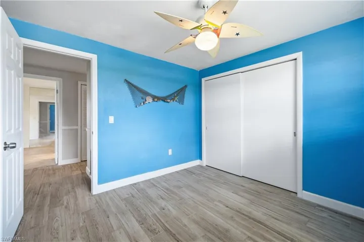Interior room featuring wood-finish flooring, a ceiling fan with integrated lighting, and a double sliding closet door