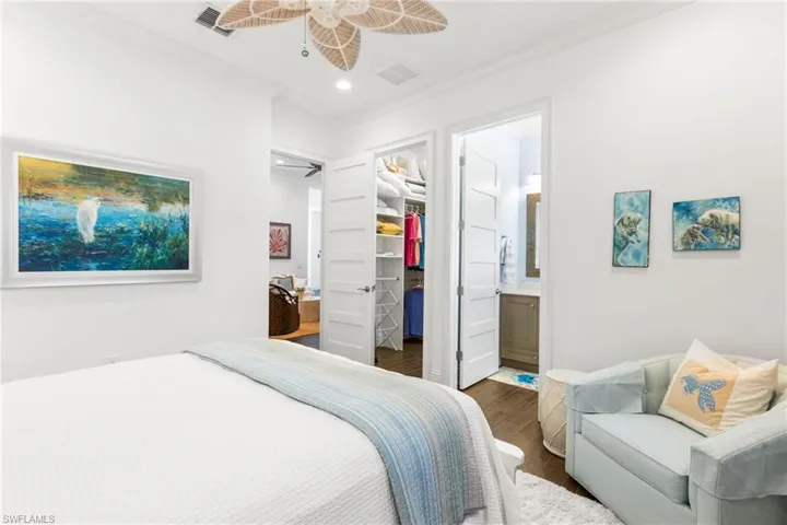 Bedroom featuring ornamental molding, ensuite bath, ceiling fan, and dark wood-type flooring