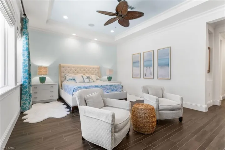 Bedroom featuring multiple windows, dark hardwood / wood-style floors, a raised ceiling, and ceiling fan
