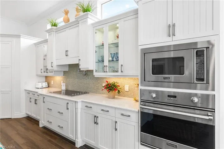 Kitchen with stainless steel appliances, tasteful backsplash, dark hardwood / wood-style flooring, crown molding, and white cabinets