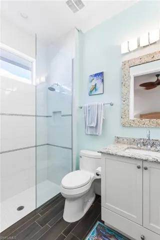 Bathroom featuring tiled shower, vanity, and toilet