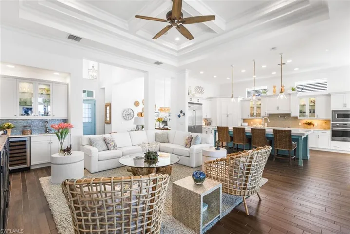 Living room featuring wine cooler, dark hardwood / wood-style flooring, crown molding, and a high ceiling