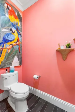 Bathroom with wood-type flooring, toilet, and crown molding