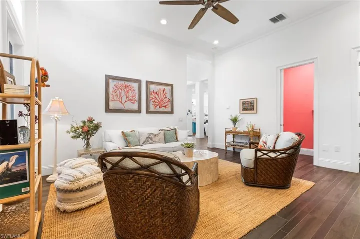 Living room featuring ceiling fan, crown molding, and dark wood-type flooring