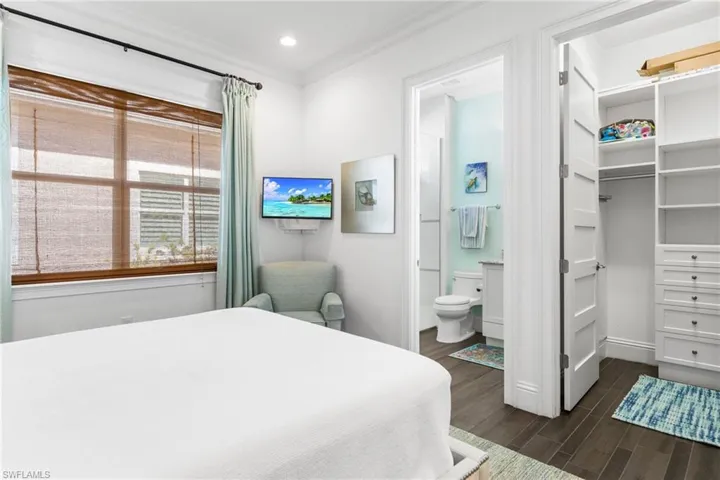 Bedroom with dark hardwood / wood-style flooring, ensuite bath, a closet, and crown molding