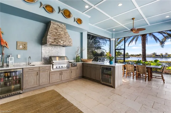 View of patio featuring area for grilling, a water view, and wine cooler