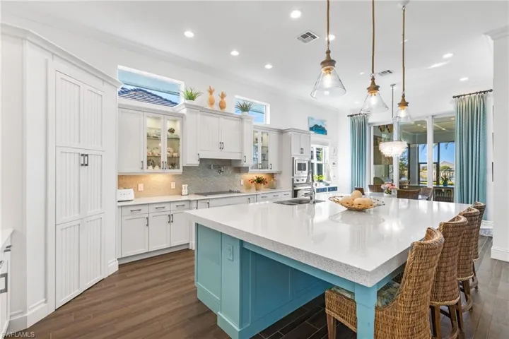 Kitchen with white cabinetry, hanging light fixtures, a spacious island, and dark hardwood / wood-style floors